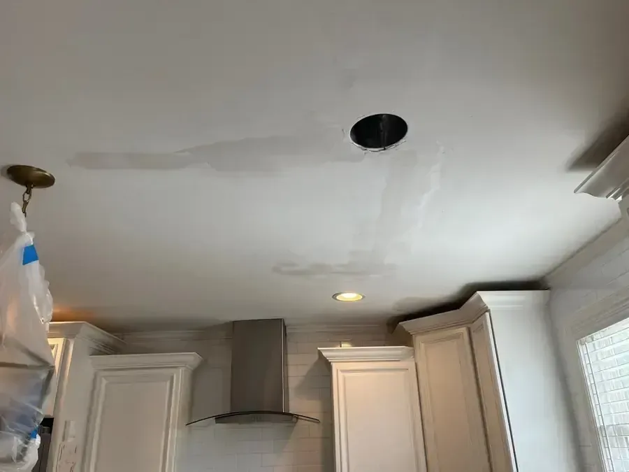 Discolored kitchen ceiling with an open light fitting above cabinets