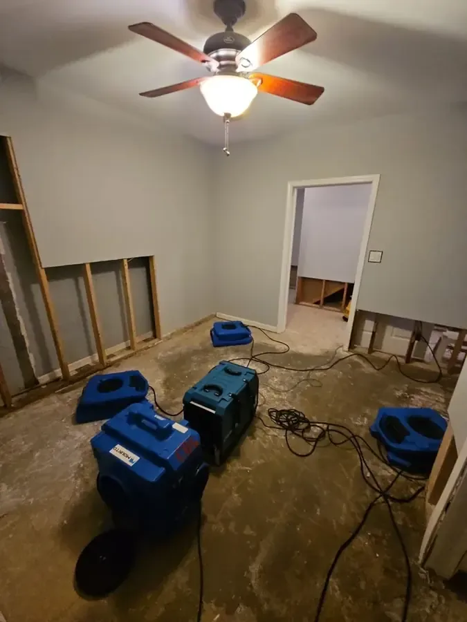 Blue drying equipment across a room with exposed lower wall framing